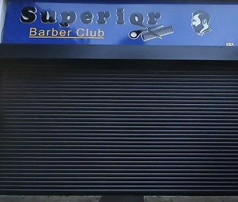 Black roller shutter closed across a barber shop frontage